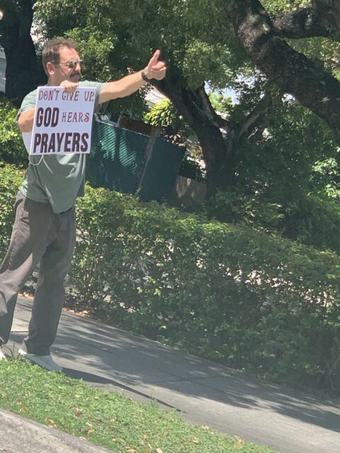 Man holding sign about prayer encouragement.