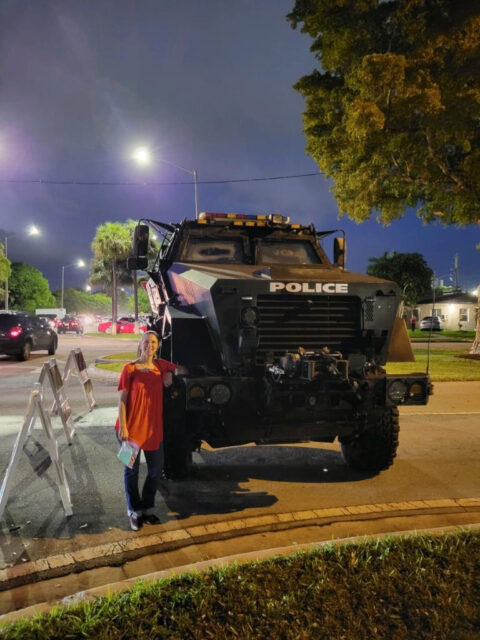 Person standing beside a police armored vehicle.