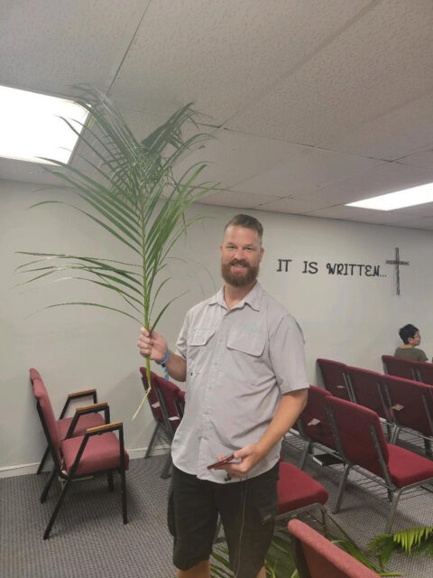 Man holding palm leaf in church setting.
