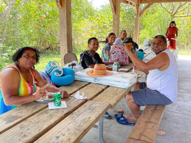 Group enjoying picnic under wooden pavilion.