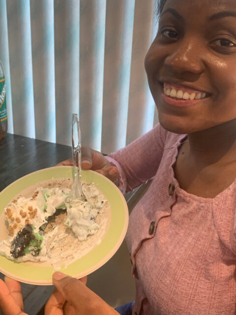 Smiling person holding a plate of dessert.