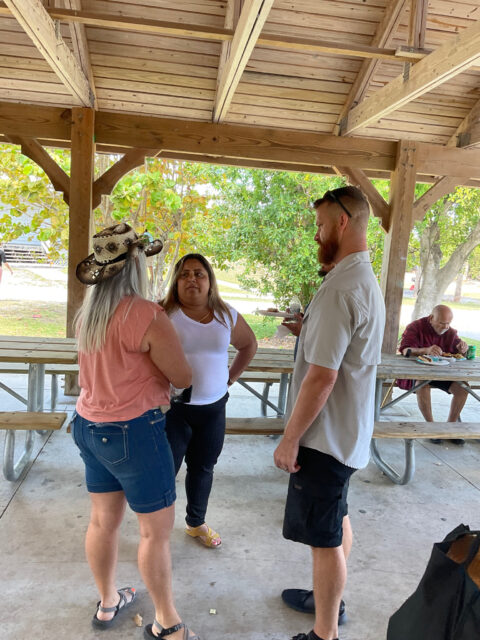 Three people talking under a pavilion.