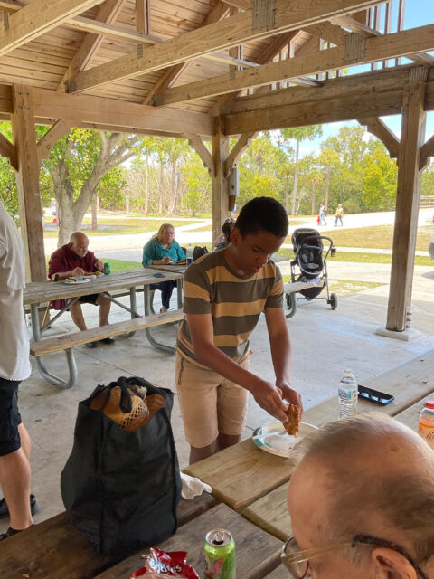 Person preparing food at a picnic table.