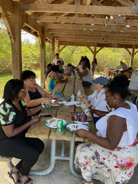 People enjoying a picnic under wooden shelter.