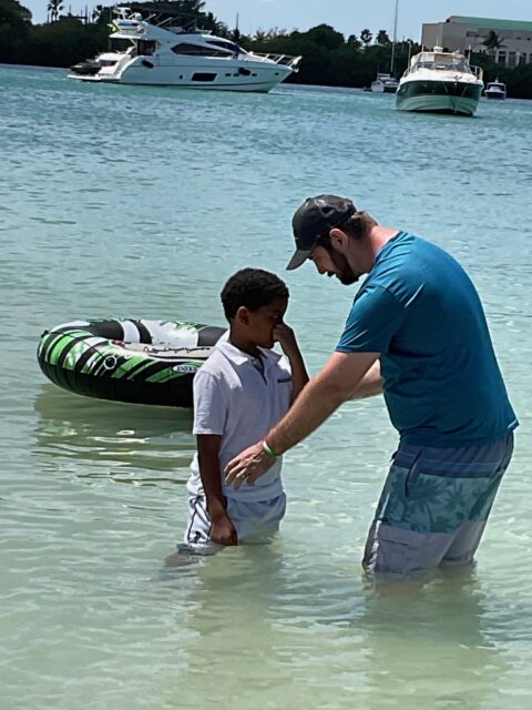 Man and boy standing in shallow water.
