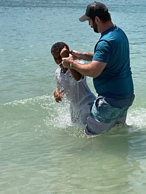 Two people in water, one baptizing another.