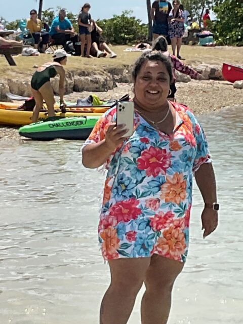 Smiling woman holding phone near the water.
