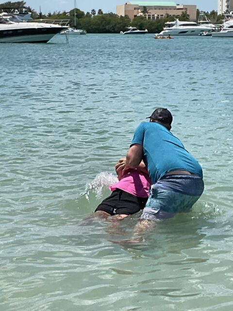 Two people playing in shallow ocean water.