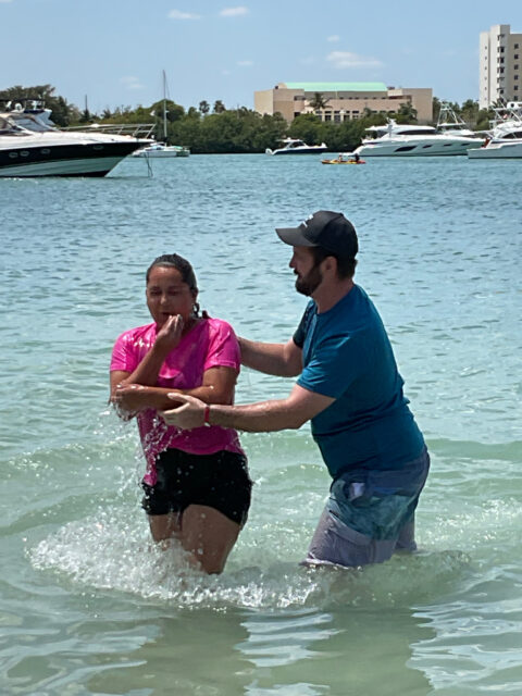 Two people in water near boats.