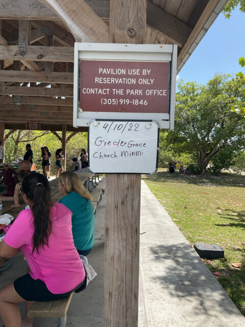 Park pavilion with reservation sign and people.