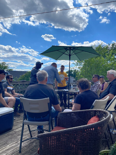 Outdoor gathering with people under a parasol.