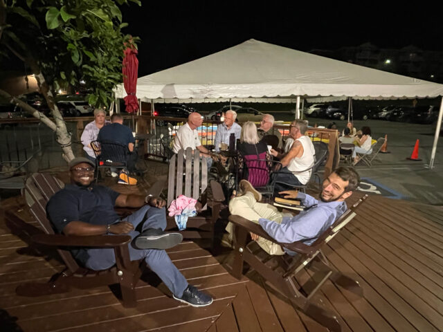 Outdoor gathering under a tent at night.