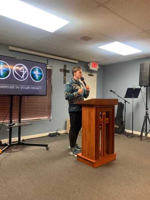 Man speaking at church podium with microphone.