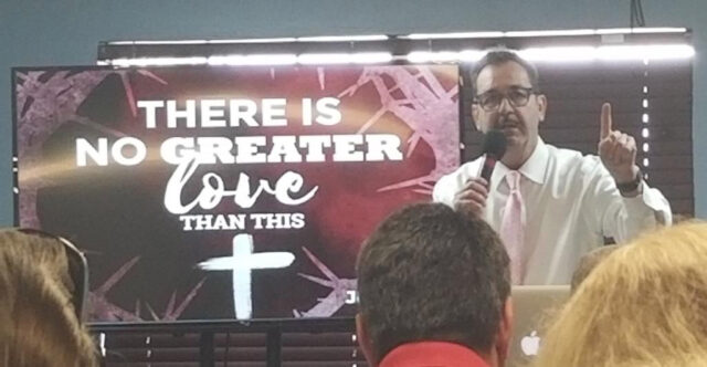 Speaker presenting with inspirational slide background.