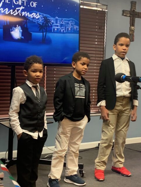 Three boys dressed in suits performing.