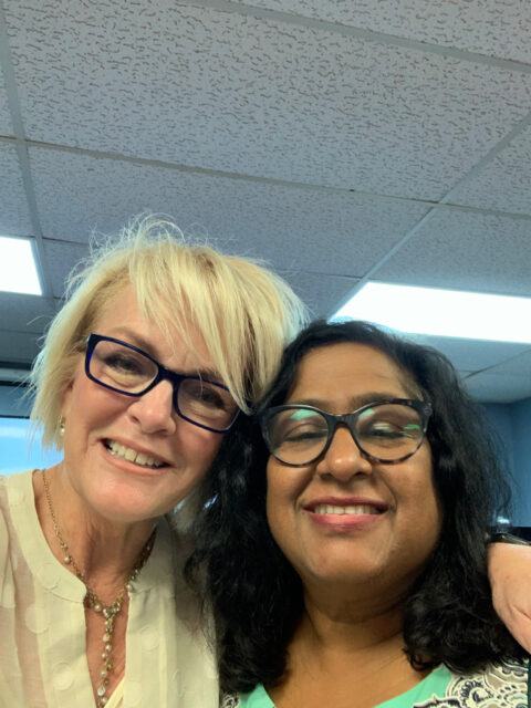 Two women smiling together in an office.