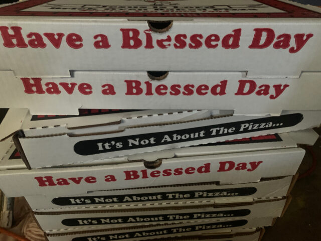 Pizza boxes with inspirational messages stacked.