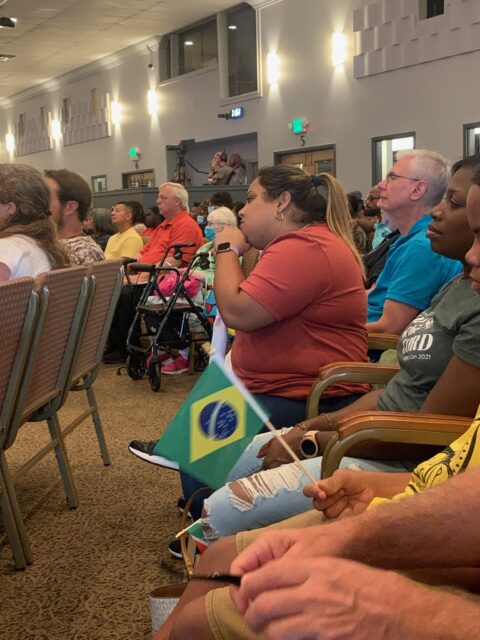 Audience seated with a small Brazilian flag.