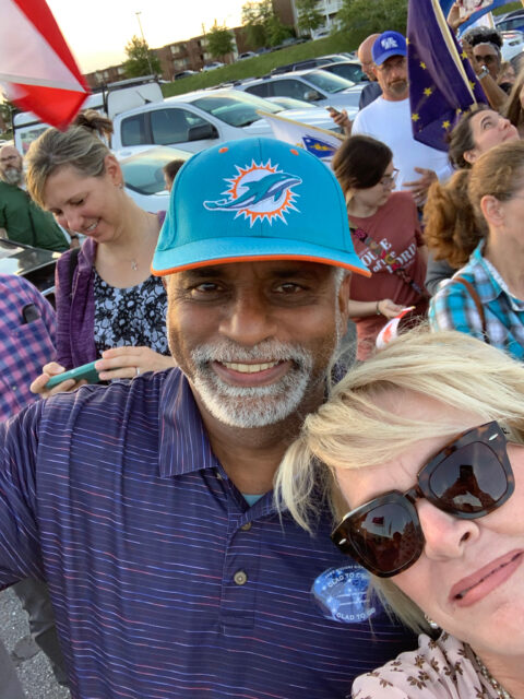 Smiling man wearing Miami Dolphins cap outdoors.