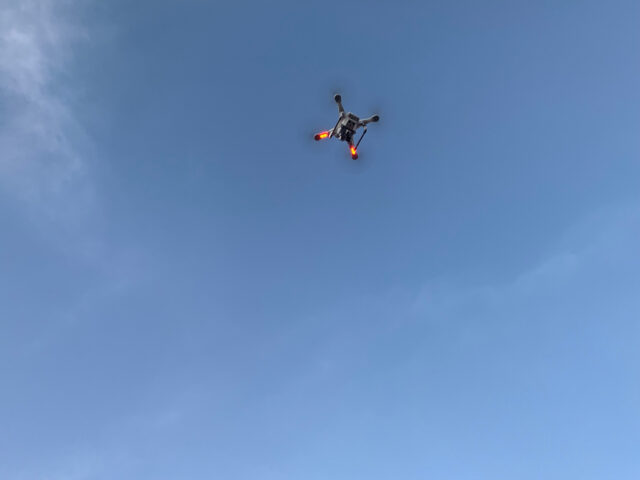 Drone flying in a clear blue sky.