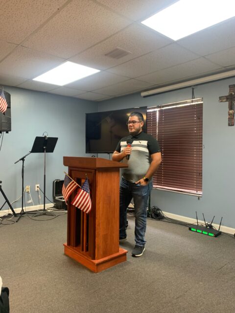 Man speaking at podium in decorated room.