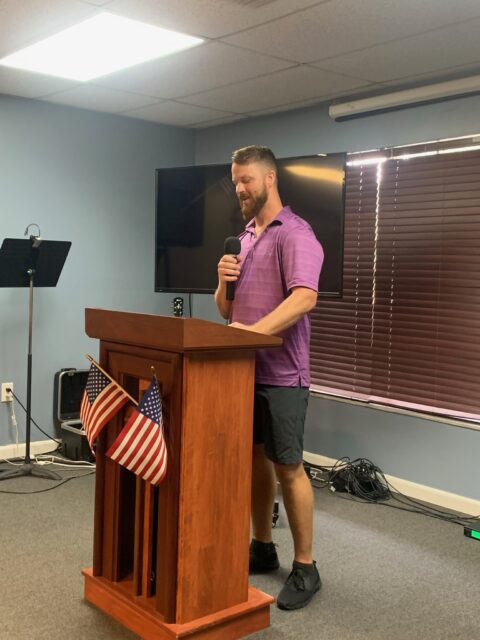 Man speaking at podium with American flags.