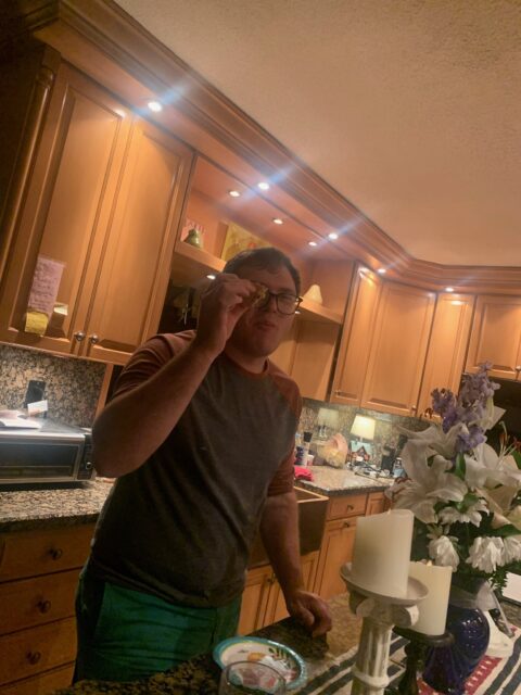 Man standing in a kitchen, holding glasses.