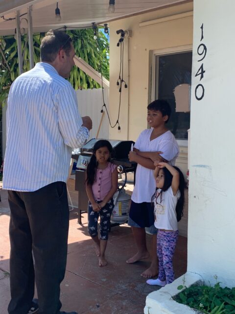 Man talking to three children outside house.
