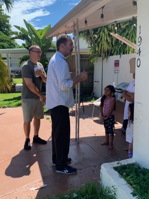 People talking outside a house with children.