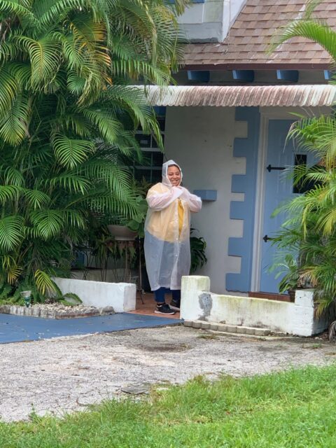Person wearing raincoat outside a house.