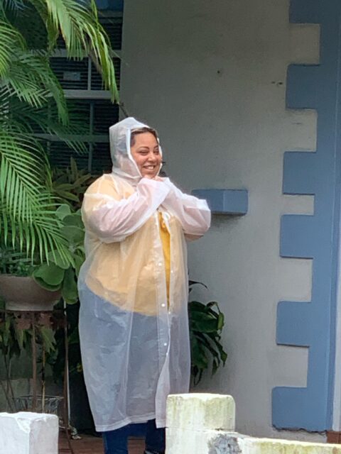 Person smiling in a clear raincoat outside.