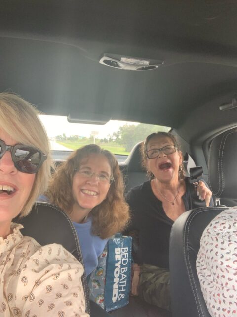 Three women smiling inside a car.
