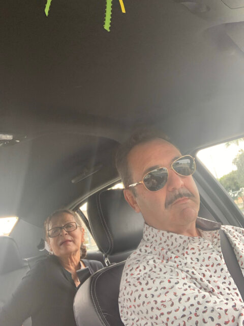 Man driving, woman sitting in back seat.