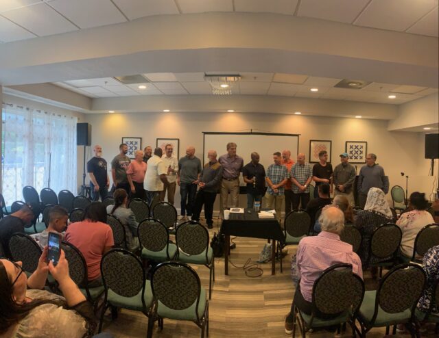 Group of people standing in a conference room.