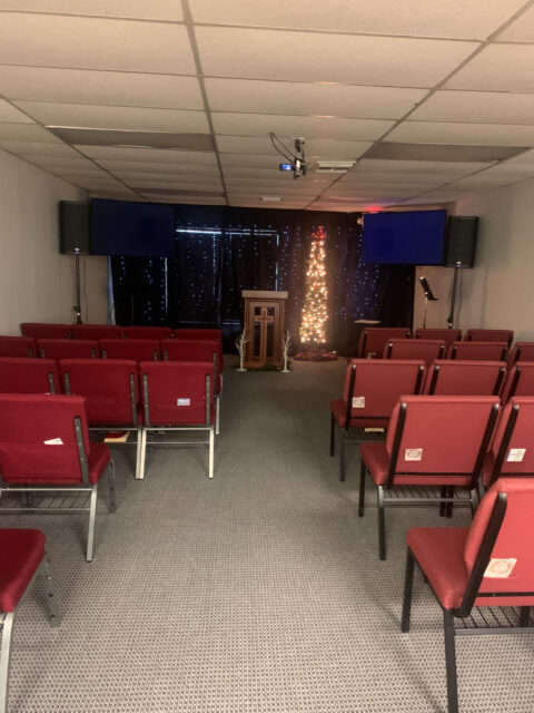 Small church interior with red chairs.