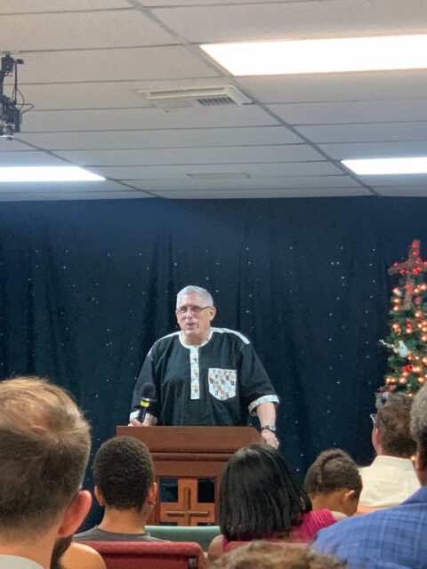 Man speaking at indoor event podium.