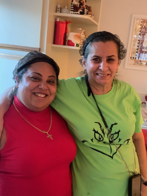 Two smiling women posing together indoors.