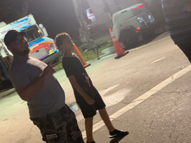 Two people walking near ice cream truck.