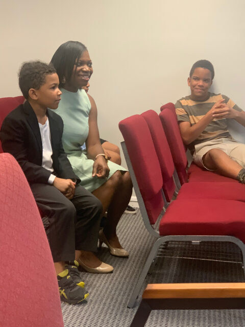 People sitting on red chairs, smiling.