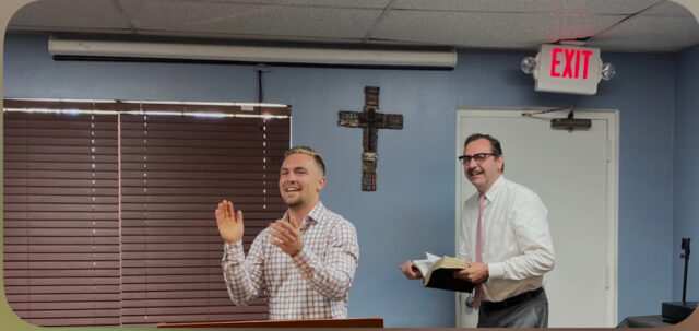 Two men clapping and smiling in church.