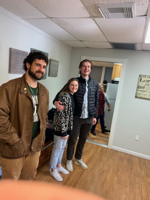 Three people standing in a room, smiling.