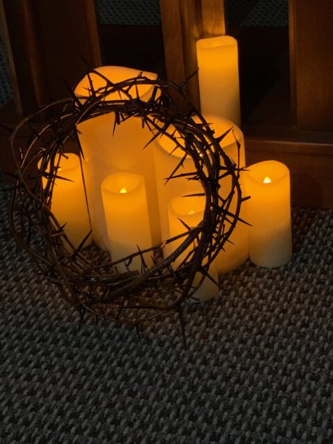 Candles with crown of thorns on carpet.