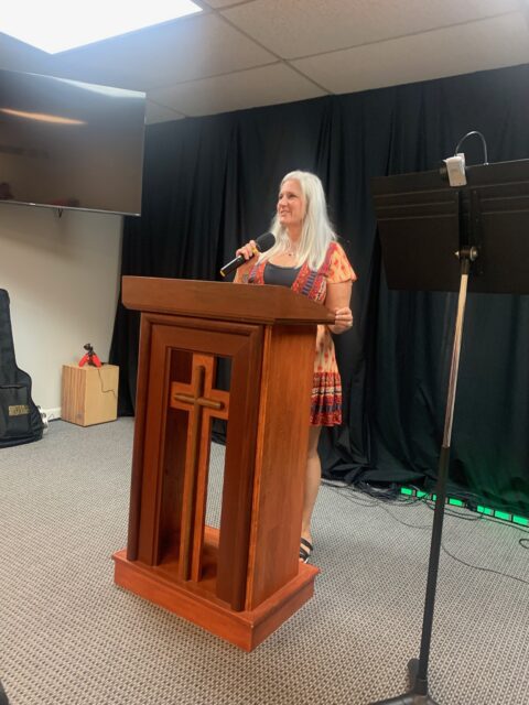Woman speaking at church podium with microphone.