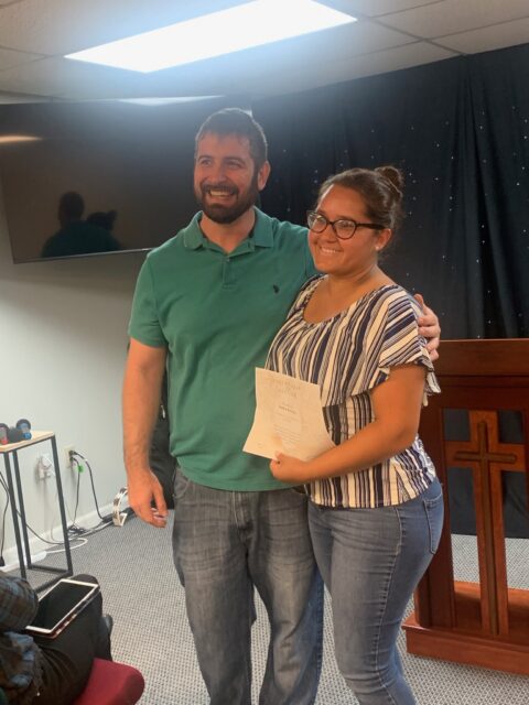 Two people smiling with certificate indoors.