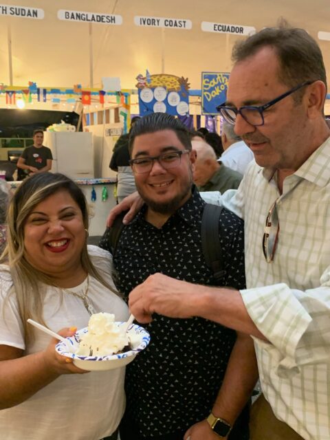Three people smiling, holding dessert plate.