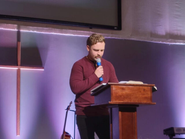 Man speaking at podium in church setting.