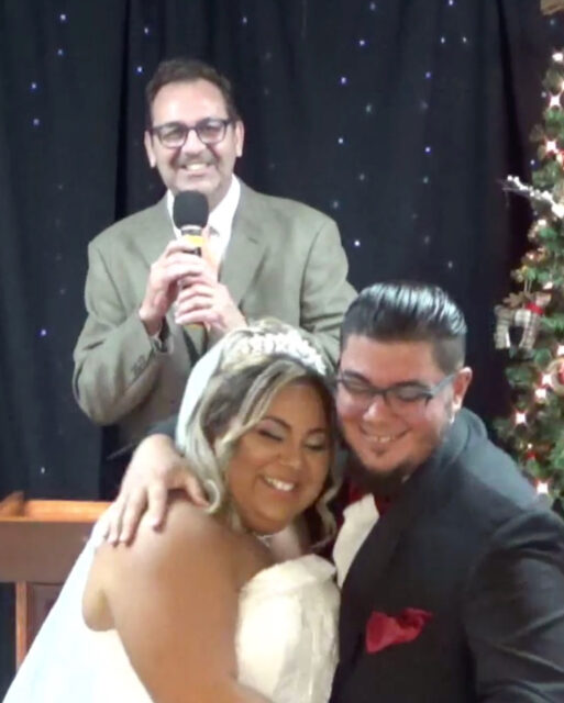 Bride and groom smiling with officiant.